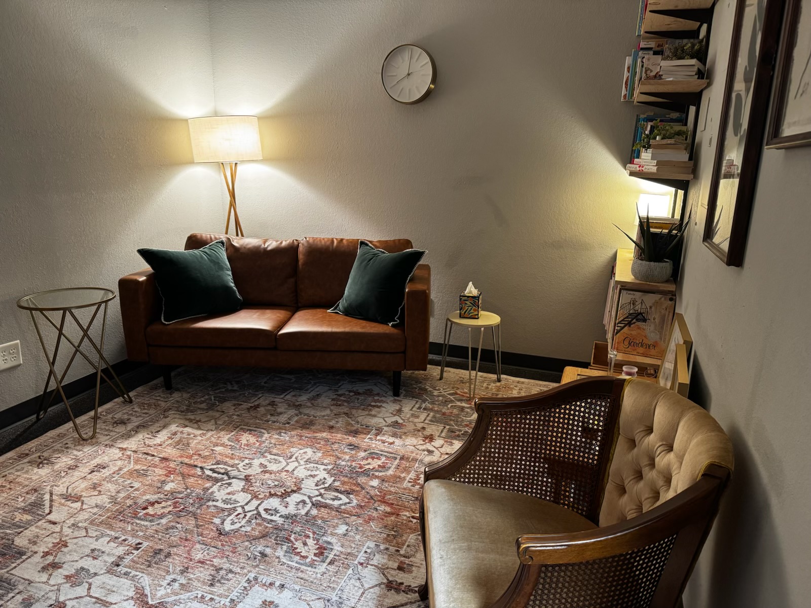 The couch and client chair, with a wall clock, lamp, and side table.